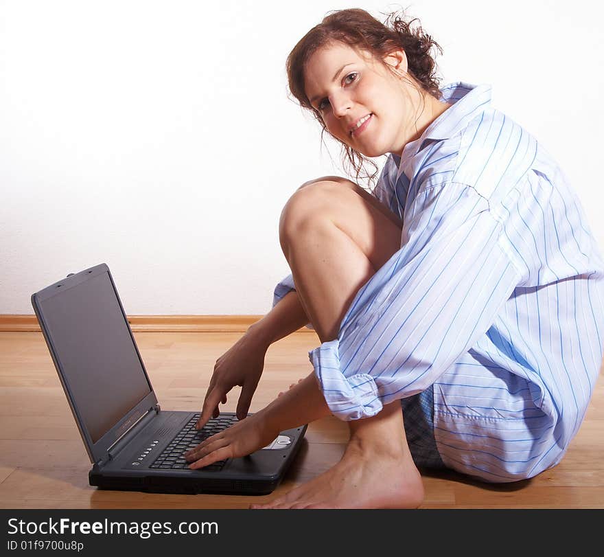 A young woman at home with her laptop sitting on the floor. A young woman at home with her laptop sitting on the floor.