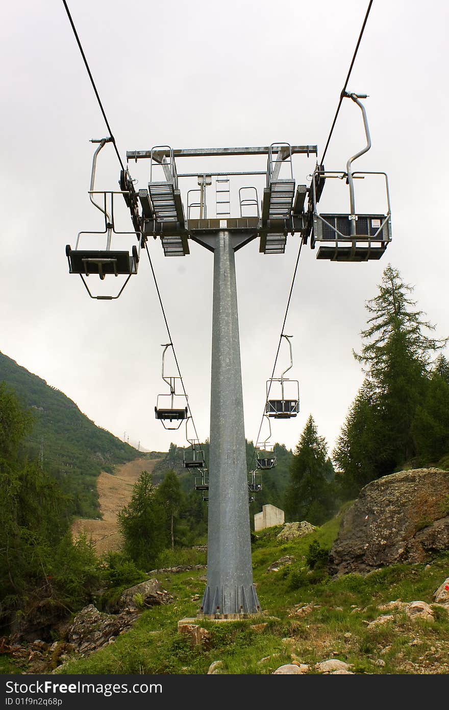 Empty chairlift between woods and rocks. Empty chairlift between woods and rocks