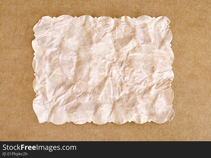 Old rectangle crumpled brown paper, with cut scalloped edges, isolated with cardboard border, copy space. Old rectangle crumpled brown paper, with cut scalloped edges, isolated with cardboard border, copy space