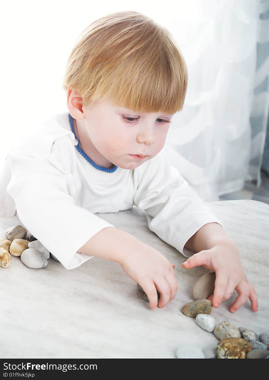 The serious little boy holds sea stones