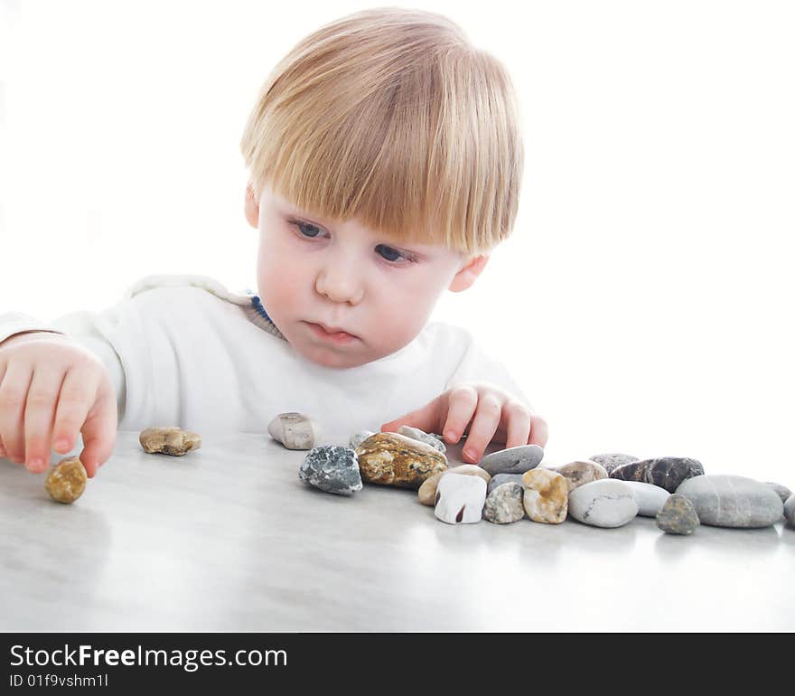 The serious little boy holds sea stones