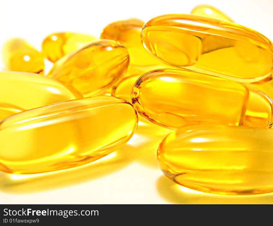 Yellow transparent capsules over a white background. Yellow transparent capsules over a white background