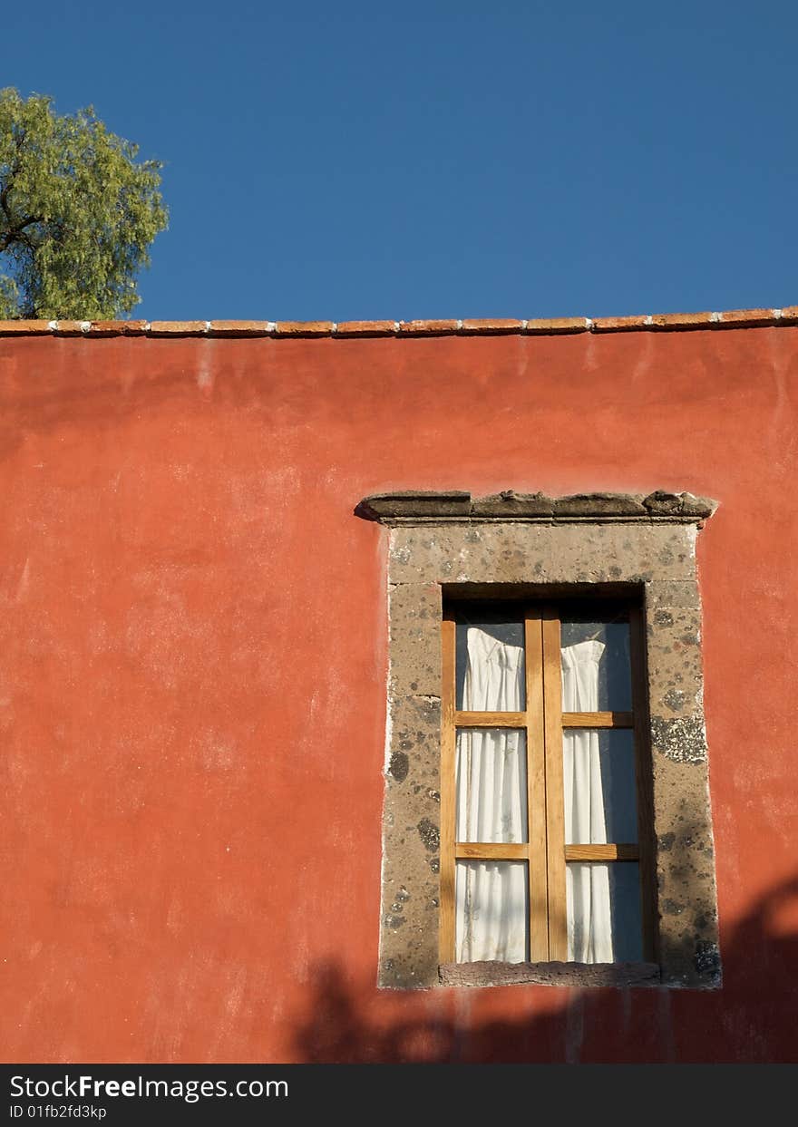 Mexican window set in burnt sienna coloured wall of Mexican house, San Miguel de Allende, Mexico.