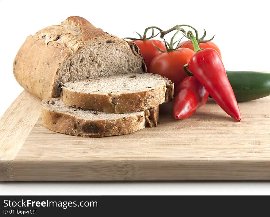 Close up of sliced olive bread with tomatoes and peppers on a cutting board. Close up of sliced olive bread with tomatoes and peppers on a cutting board.