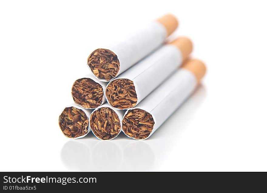 Isolated pyramid of cigarettes laying on white