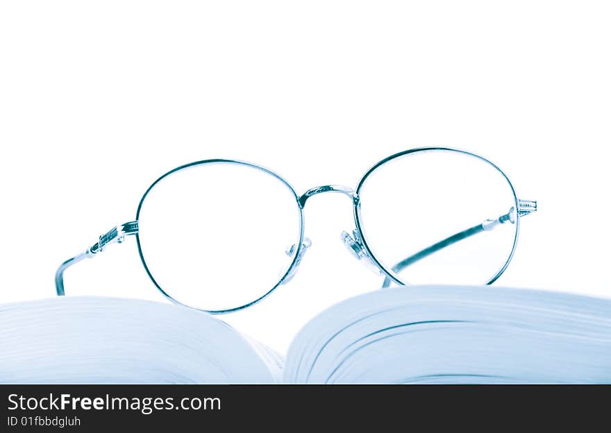 Glasses on the open book in blue tones