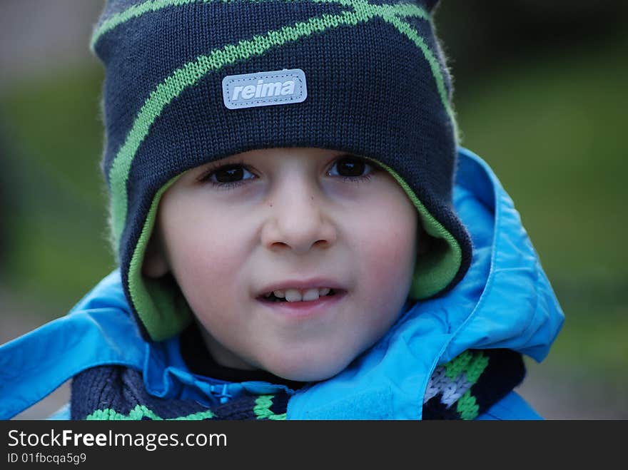 Boy in a blue jacket in a cap in an autumn park