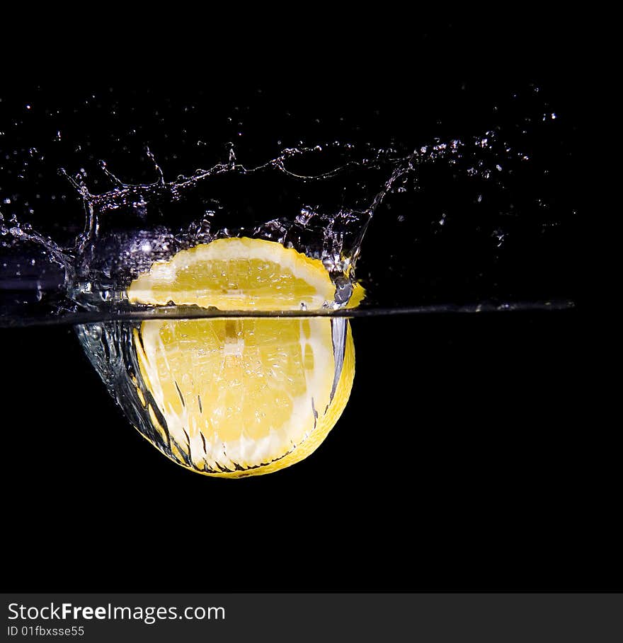 Lemon slice in water with bubbles on black ground. Lemon slice in water with bubbles on black ground