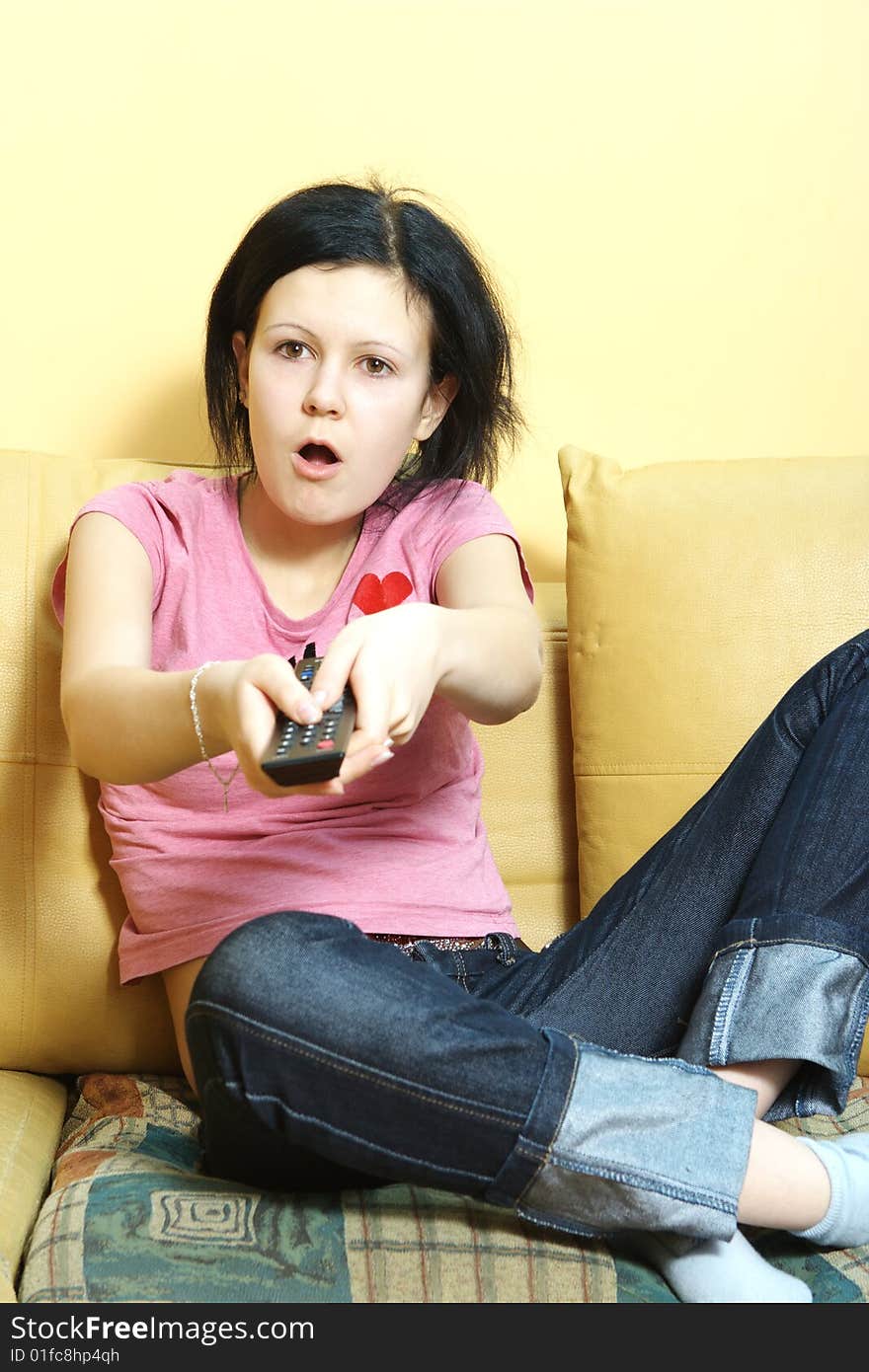 Female in blue jeans sitting on the sofa and watching TV