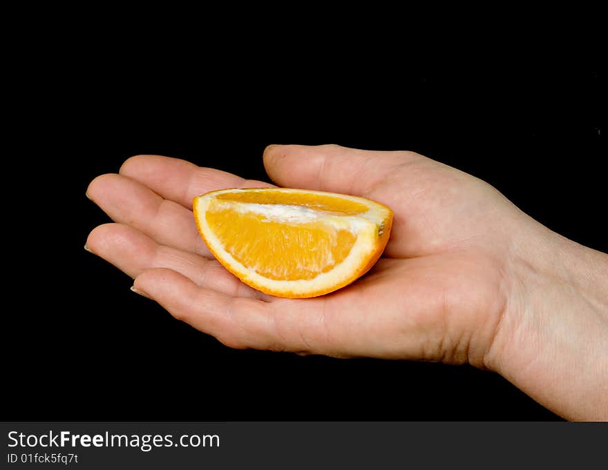 Hand with an orange slice isolated on black background