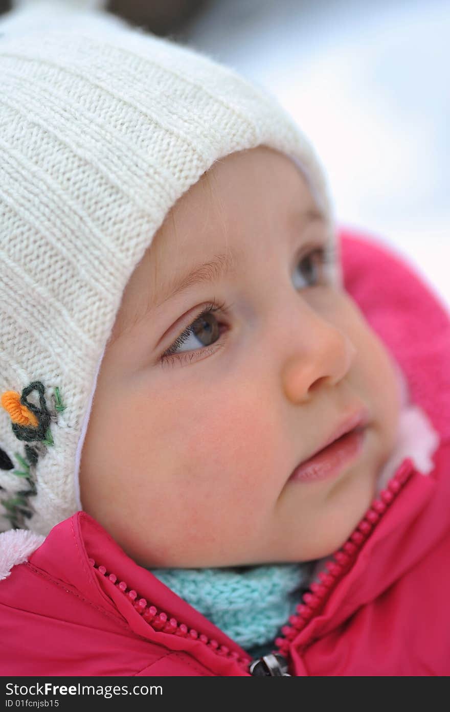 Little girl in white hat in  winter