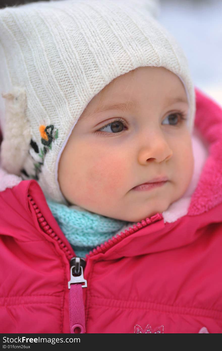 Little girl in white hat in  winter