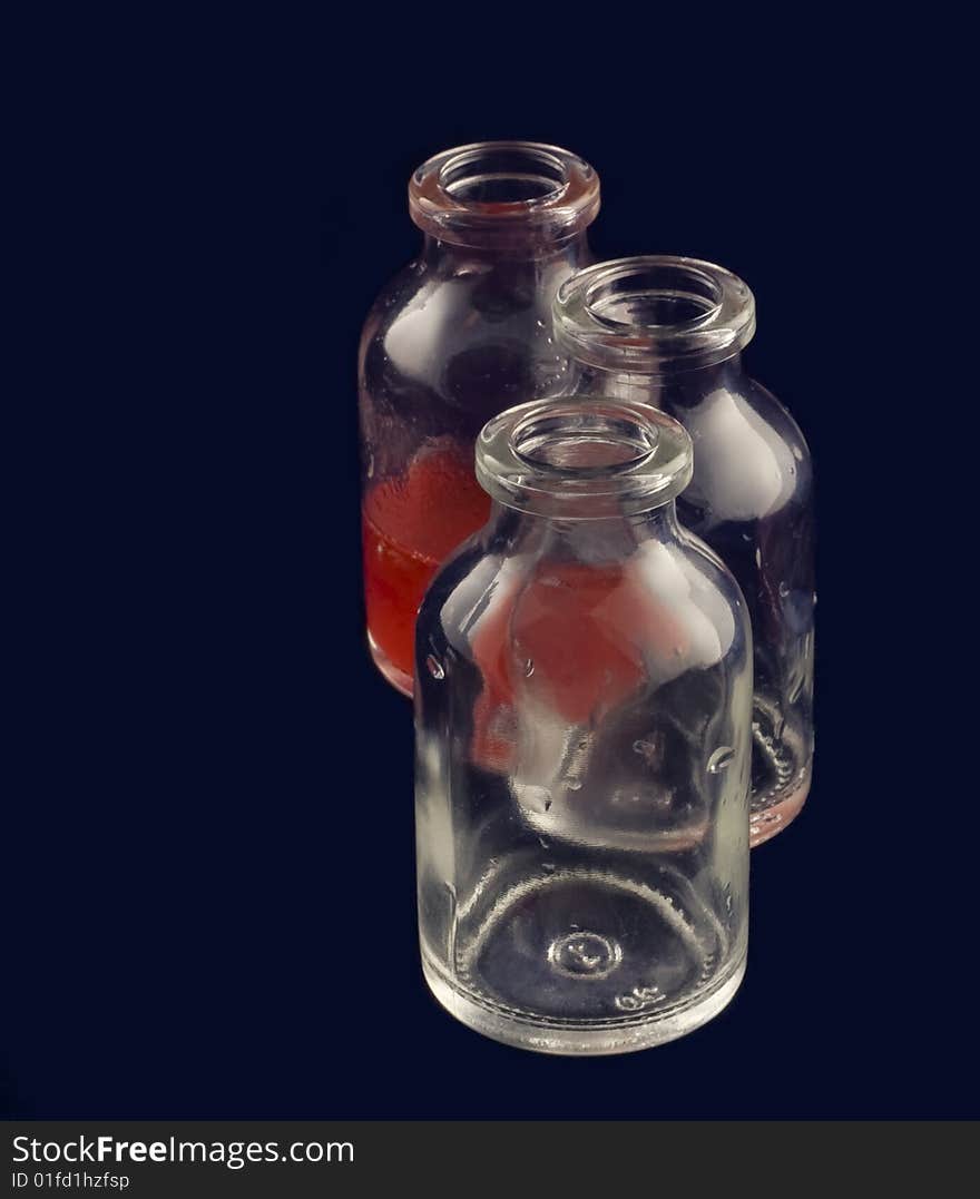 Three vials: two empty and one with red medicine