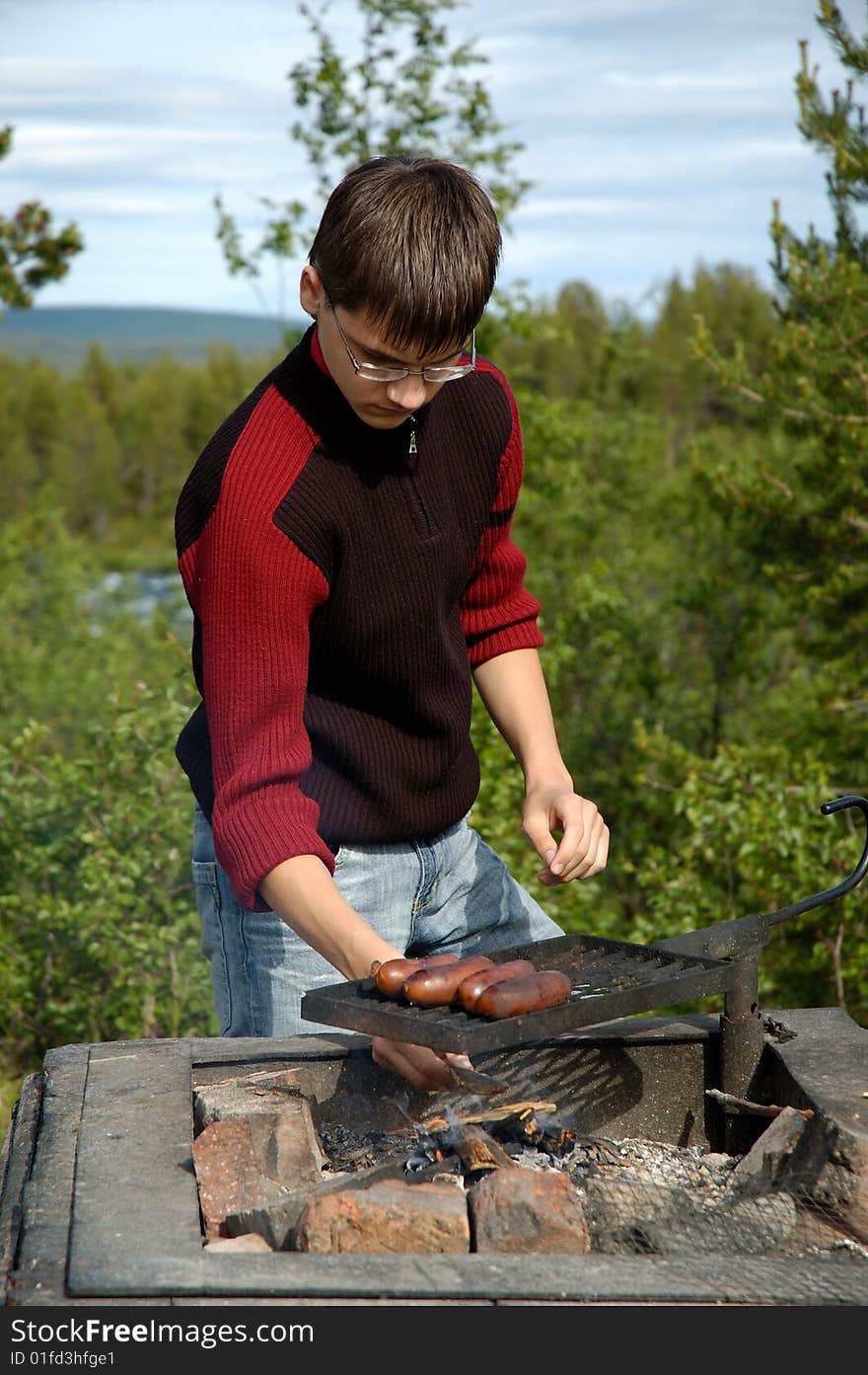 Youth roast sausages on a grill