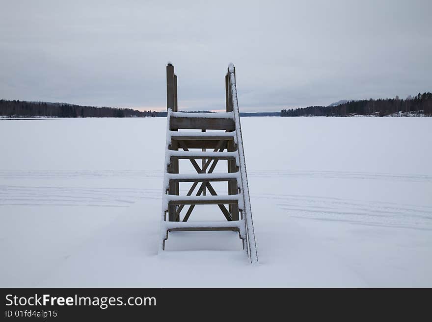 Wooden stairs at frozen lake. An empty landscape with stairs leading to nowhere. Wooden stairs at frozen lake. An empty landscape with stairs leading to nowhere.