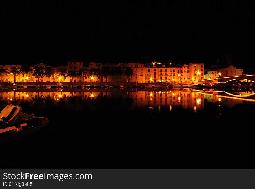 Mediterranean Town Along River Bank At Night.