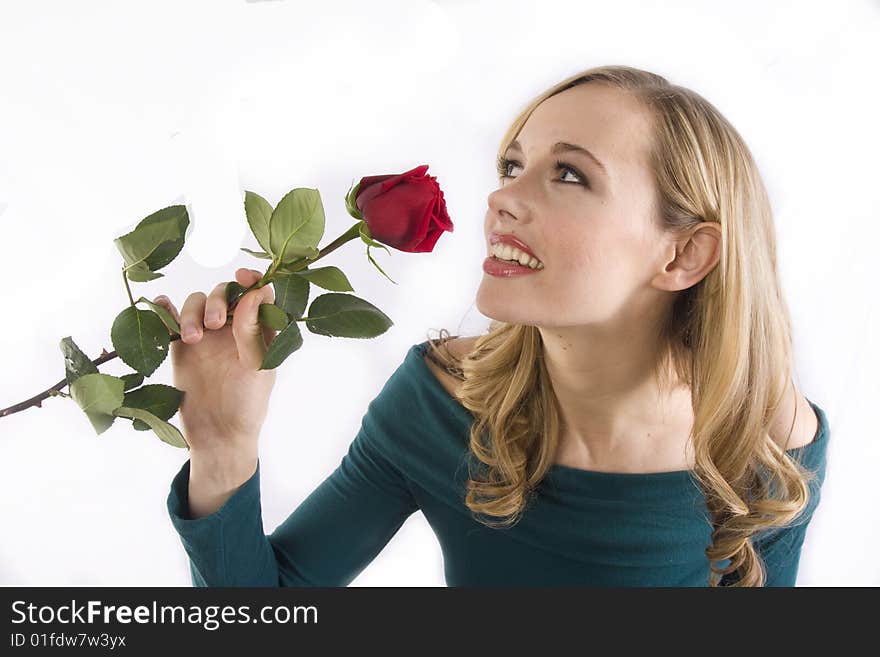 A pretty girl smells a red rose and looks off to the side. A pretty girl smells a red rose and looks off to the side