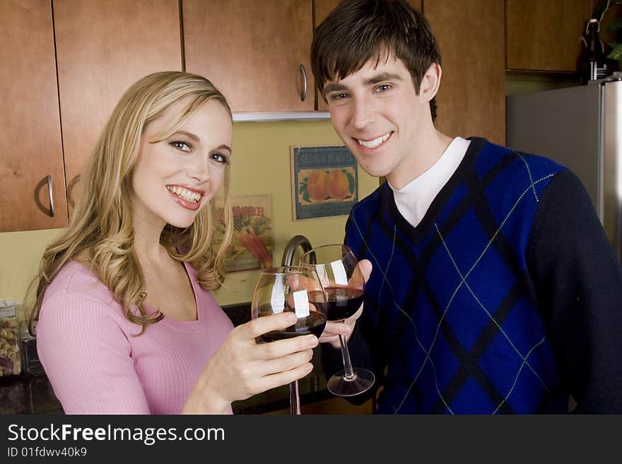 A happy couple enjoys a glass of wine in the kitchen. A happy couple enjoys a glass of wine in the kitchen