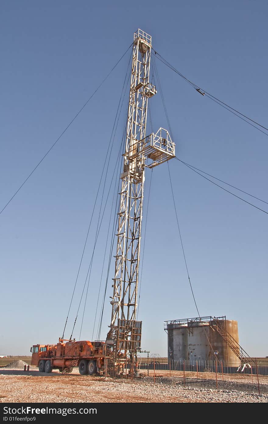 Pulling unit servicing well with the storage tanks in the background