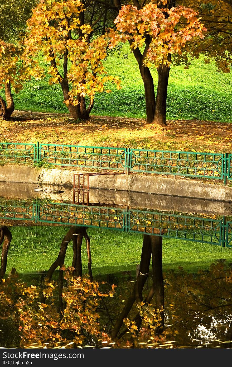 An autumn view of trees reflecting in water. An autumn view of trees reflecting in water