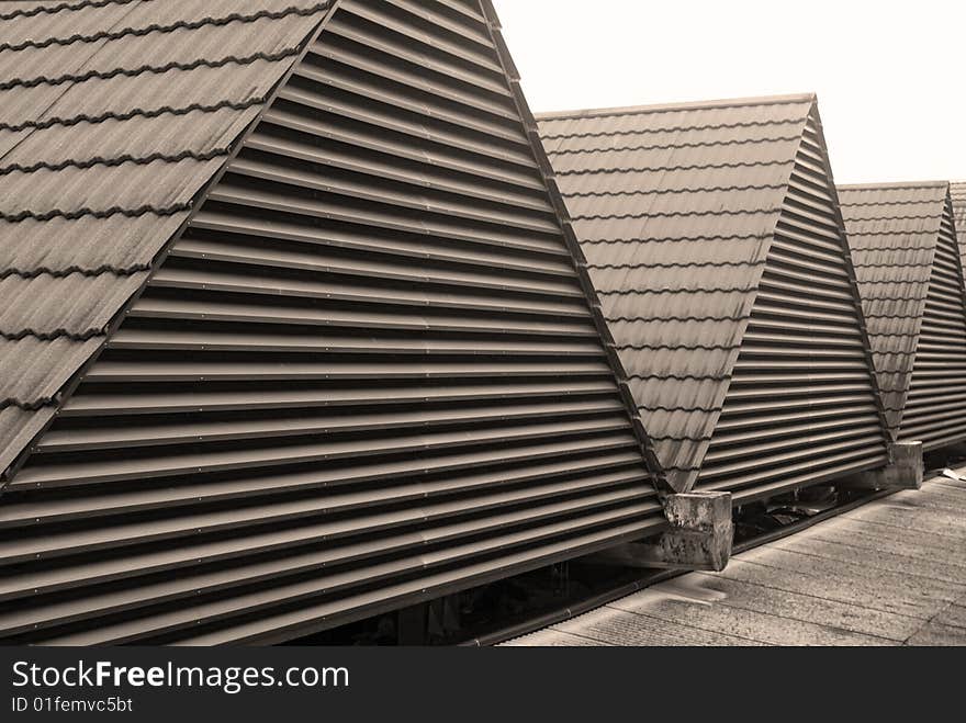 A row of triangular rooftops with fitted with ceramic tiles and metal railings.