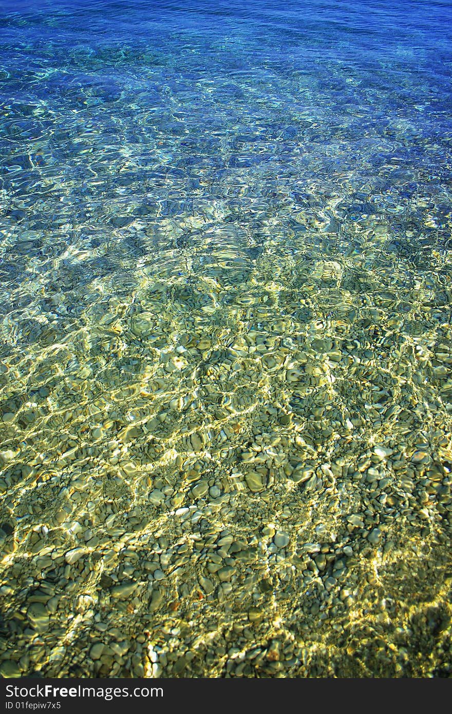 Beach pebbles under clear water with waves. Beach pebbles under clear water with waves