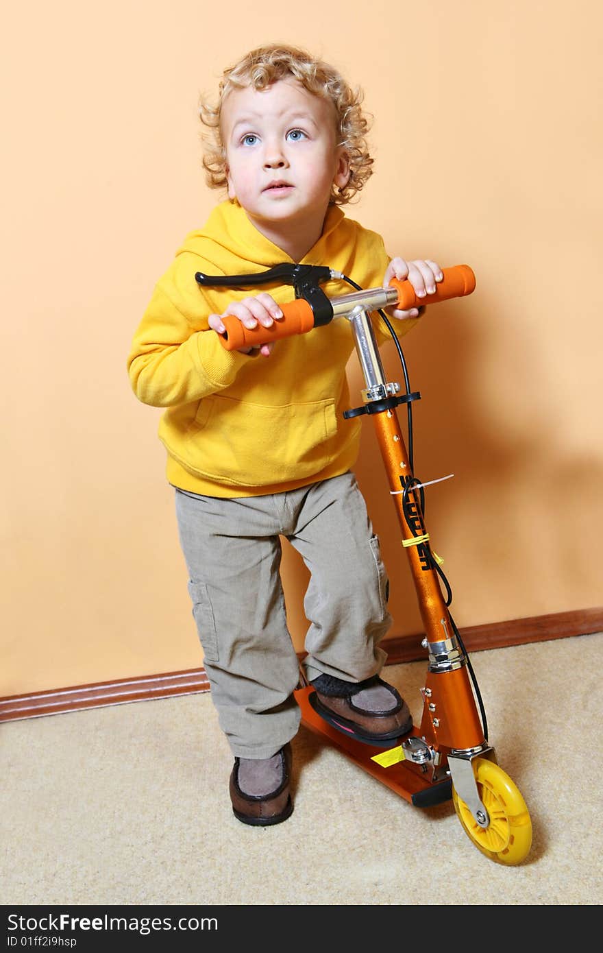 Kid with scooter stands near the wall. Kid with scooter stands near the wall.