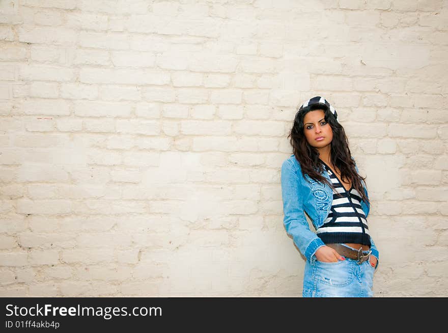 A young Asian female in denim jacket and skirt against a whitewashed brick background. A young Asian female in denim jacket and skirt against a whitewashed brick background.