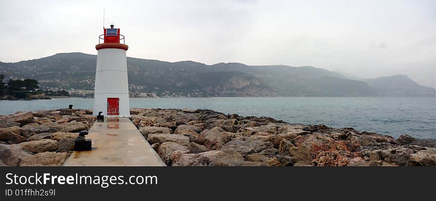 A light house on a pier overlooking the bay of Beaulieu on the Riviera. A light house on a pier overlooking the bay of Beaulieu on the Riviera