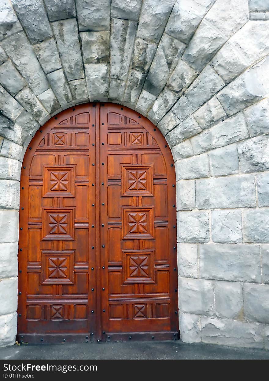 Wooden sculptured door set in a natural stone frame. Wooden sculptured door set in a natural stone frame