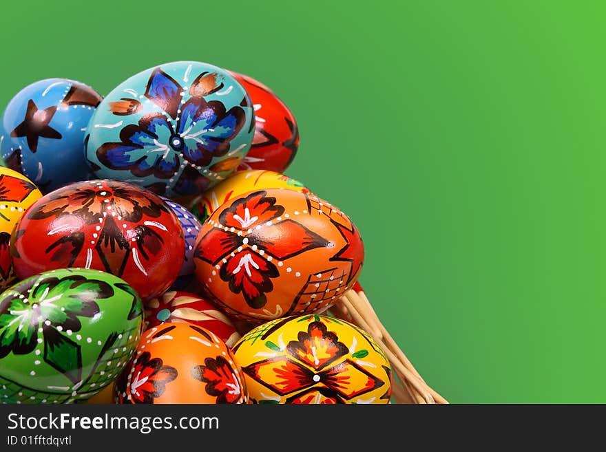 Colorful Easter Eggs in Basket on green background