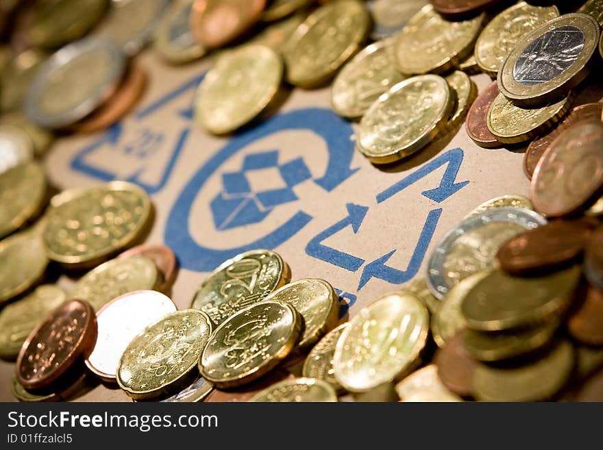 Recycling sign on cardboard with euro coins. Recycling sign on cardboard with euro coins