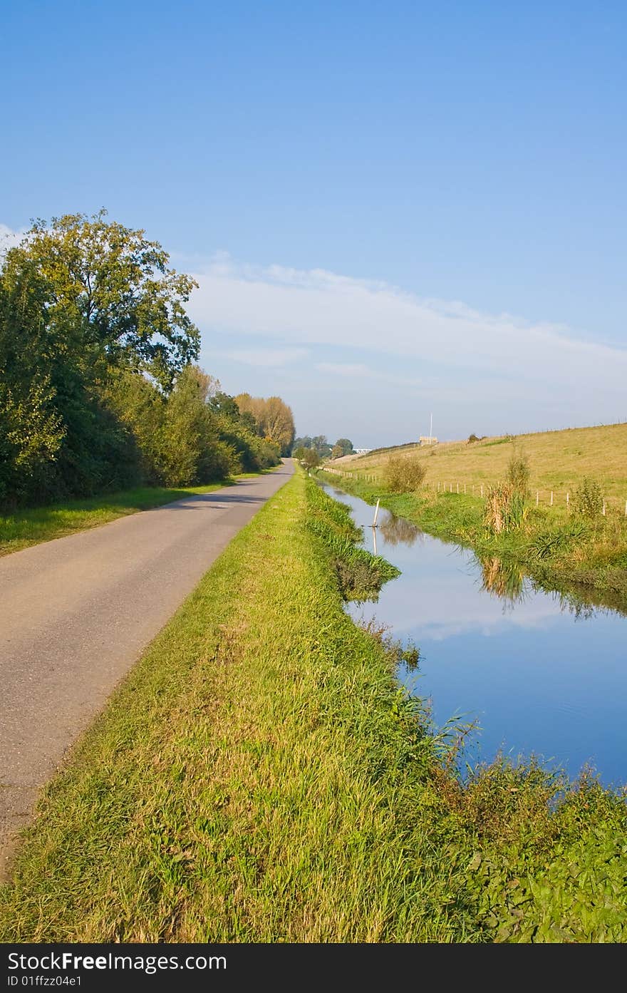 Green dike with a ditch and reflection in the water