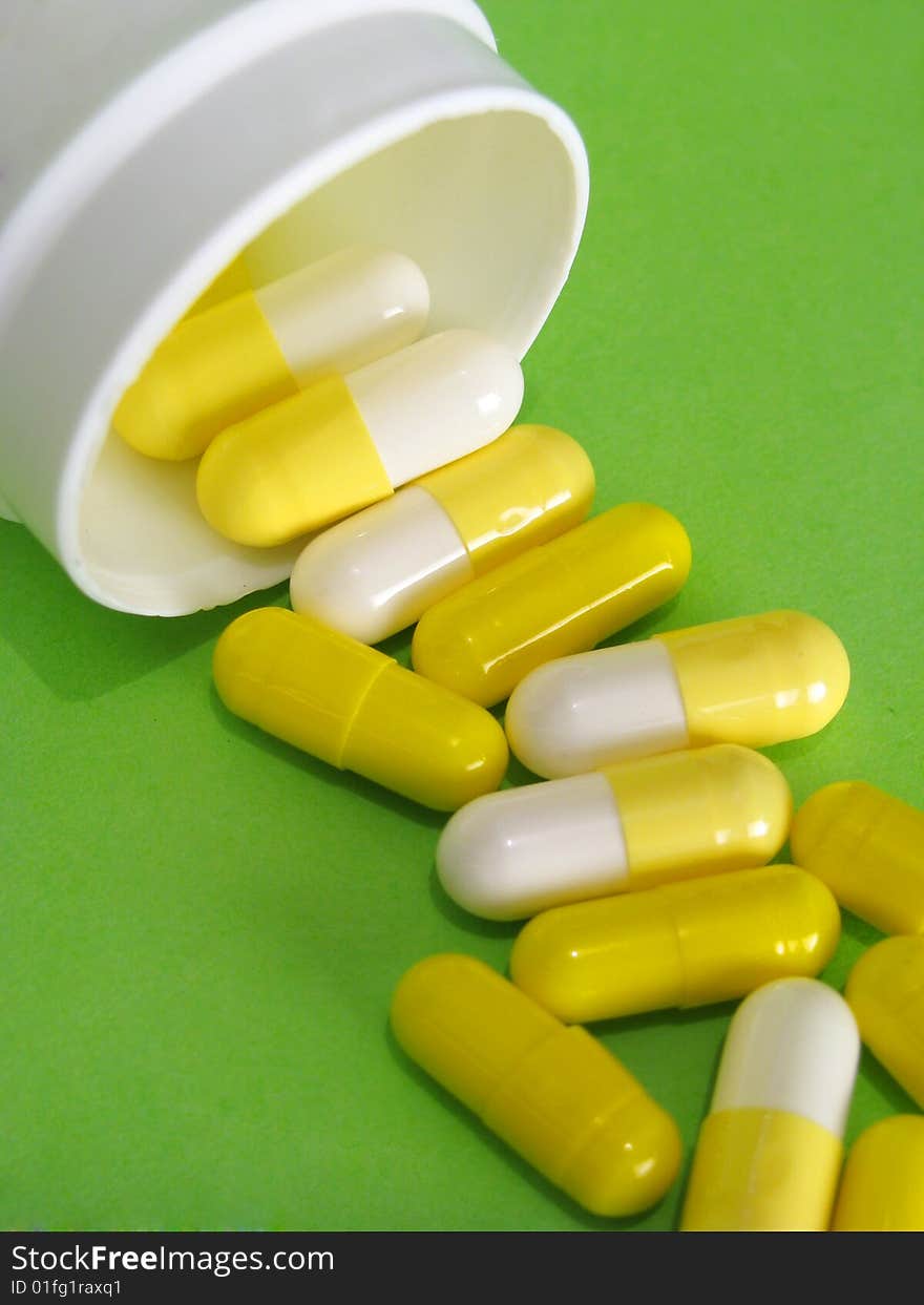 Yellow pills spilled on green