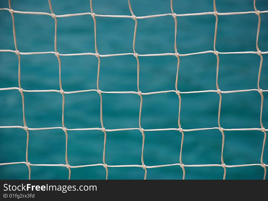 Close-up of a nautical net from the side of a sailboat with only the net and the tropical sea in sight. Close-up of a nautical net from the side of a sailboat with only the net and the tropical sea in sight.