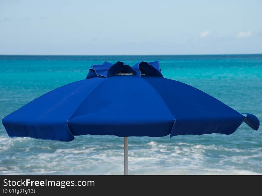 Blue umbrella on beach with tropical sea in the background. Blue umbrella on beach with tropical sea in the background.