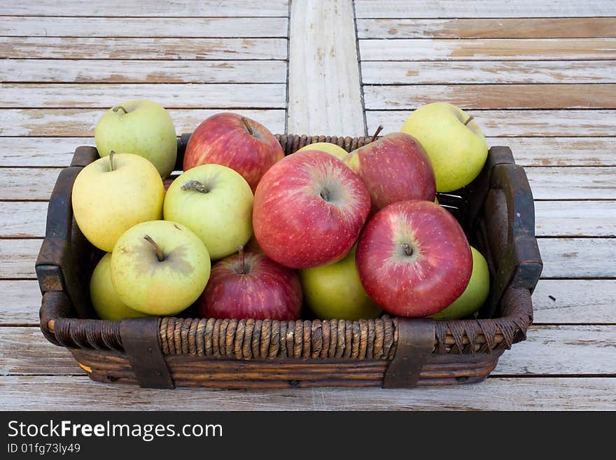 Yellow, green and red apples in a brown basket. Yellow, green and red apples in a brown basket