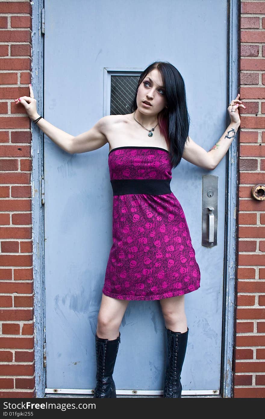 Pretty woman with jet black hair wearing a purple sleeveless dress and high boots looking upward. Pretty woman with jet black hair wearing a purple sleeveless dress and high boots looking upward