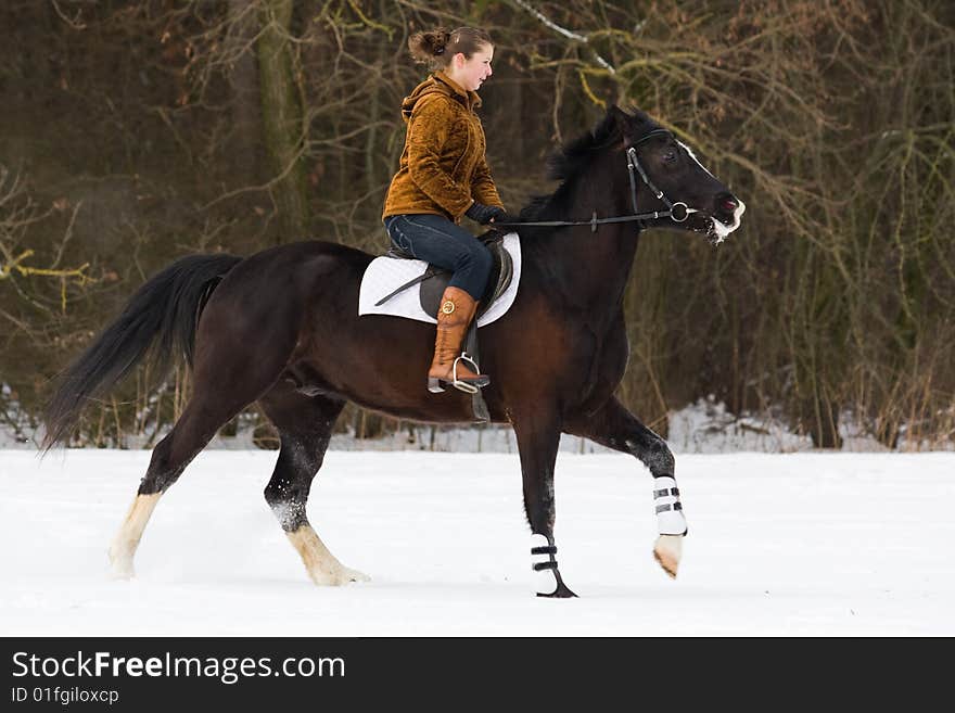 The girl is riding a horse in a winter forest