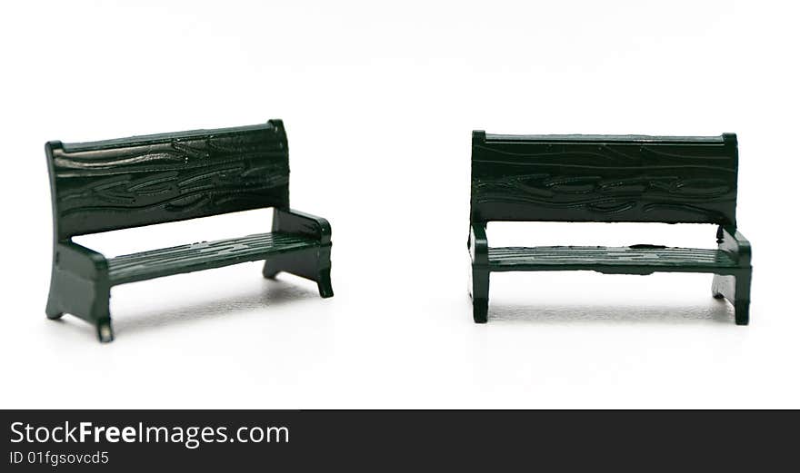 Two miniature green metal benches on white background. Two miniature green metal benches on white background.