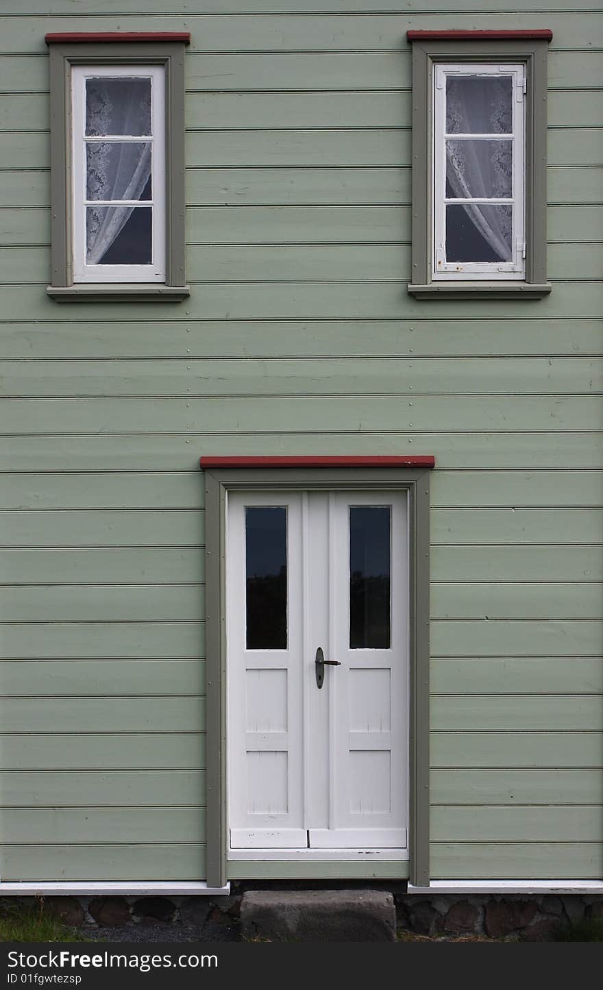 Green painted front on a wooden house, doorway and windows form a sort of a face. Green painted front on a wooden house, doorway and windows form a sort of a face