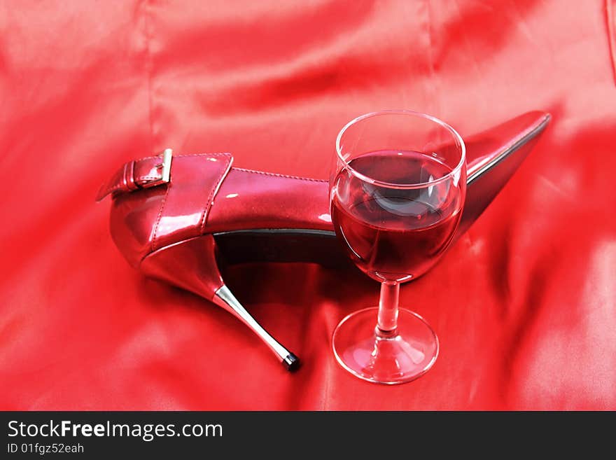 Red wine and shoe on red satin background. Red wine and shoe on red satin background