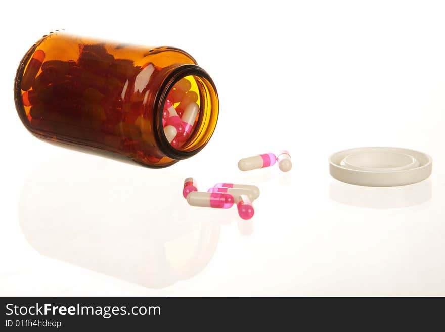 Pills spilling from a pill bottle, isolated on white with copy space. High key lighting. Pills spilling from a pill bottle, isolated on white with copy space. High key lighting