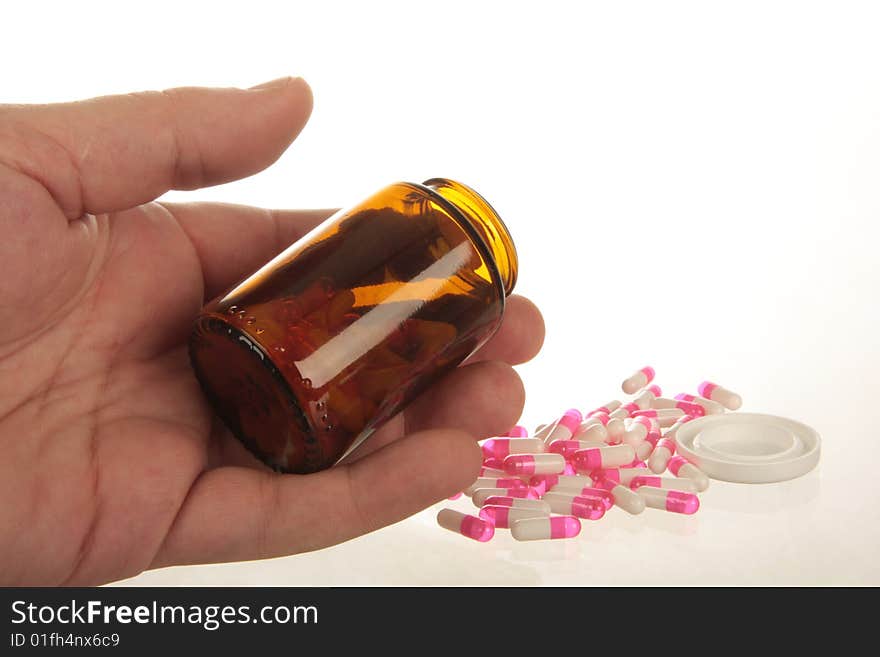 Human hand holding a pill bottle with pill capsules spilling out, shot on white, concept of overdose, addiction or suicide. Human hand holding a pill bottle with pill capsules spilling out, shot on white, concept of overdose, addiction or suicide