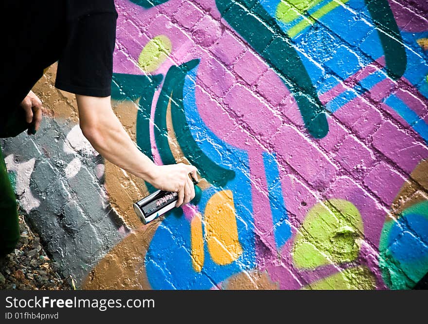 Graffiti Artist At Work spraying on a textured brick wall downtown Auckland.