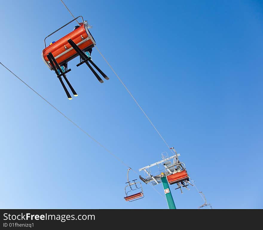 Skiers are riding in chairlift in a ski area, low angle view, Italy. Large copy-space at the top.