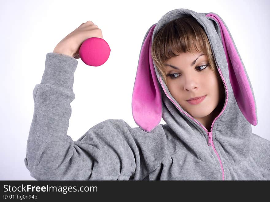 Pretty girl holds pink dumbbell in the hand and she is happy with the size of the muscles. Pretty girl holds pink dumbbell in the hand and she is happy with the size of the muscles