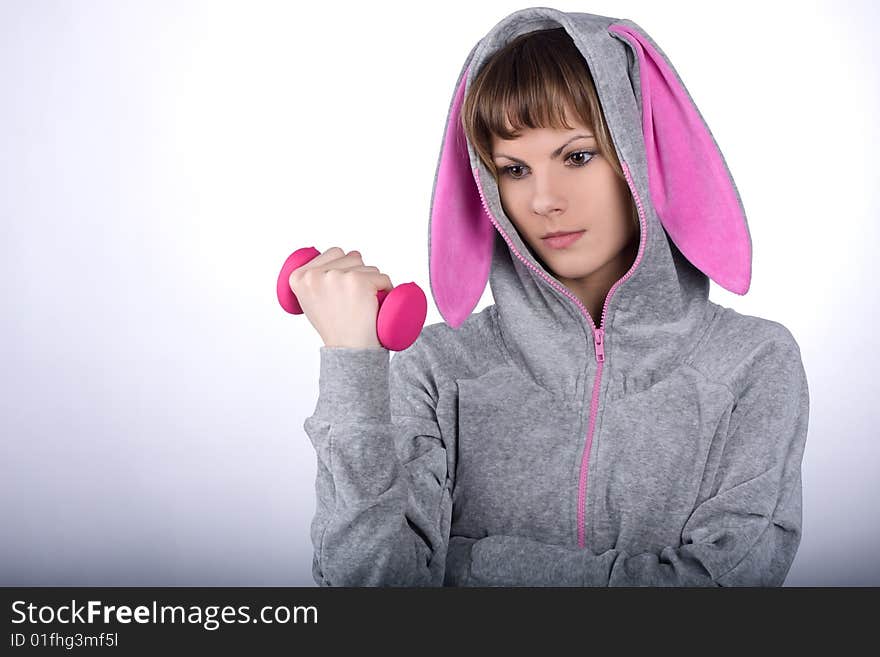 Pretty thoughtful girl holds a pink dumbbell in her hand. Pretty thoughtful girl holds a pink dumbbell in her hand