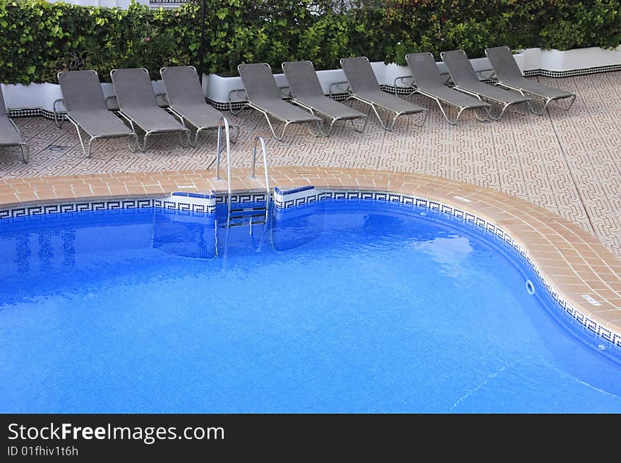 Swimming pool surrounded with sunloungers for the tourists. Swimming pool surrounded with sunloungers for the tourists