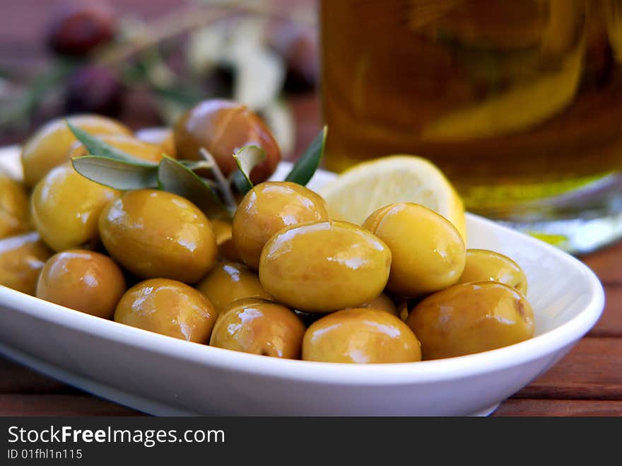 Fresh green olives and lemon in the plate